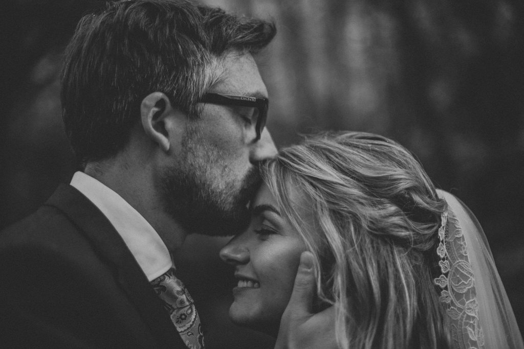 black and white close up photo bride and groom kiss on forehead