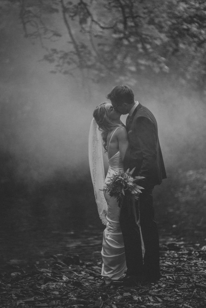 black and white photo bride groom kissing in the woods