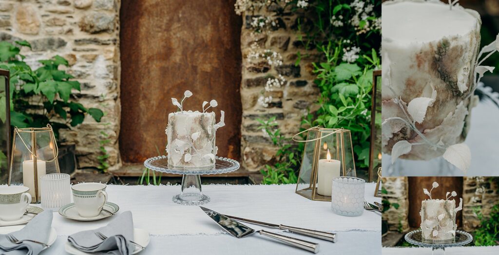 single tier bark effect wedding cake on glass stand in front of stone wall with textured sugar paste leaves