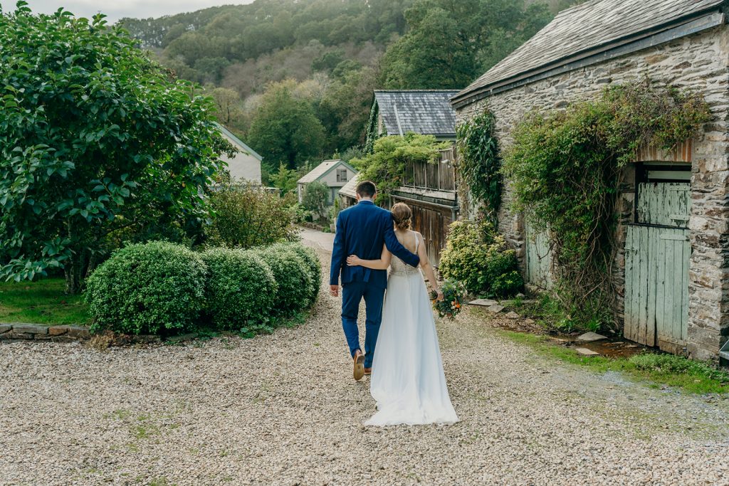 bride & groom walking away arm in arm in the Devon countryside