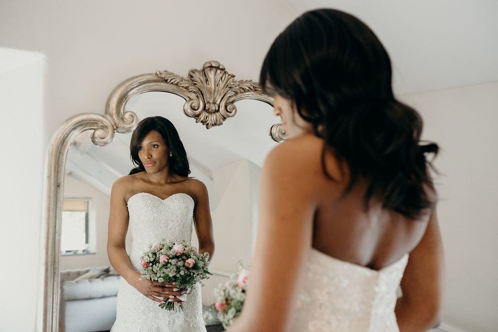 bride looking in mirror at self in wedding dress
