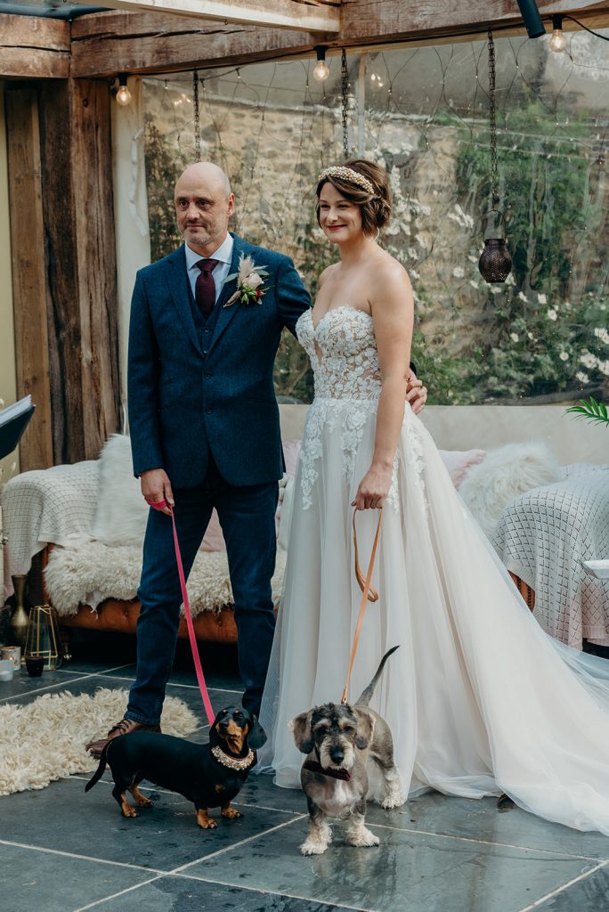 Bride and groom getting married each holding a dog on a lead