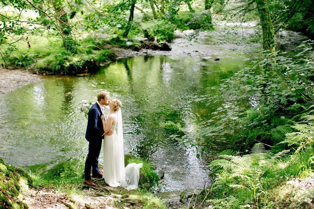 Bride and groom kissing by the river