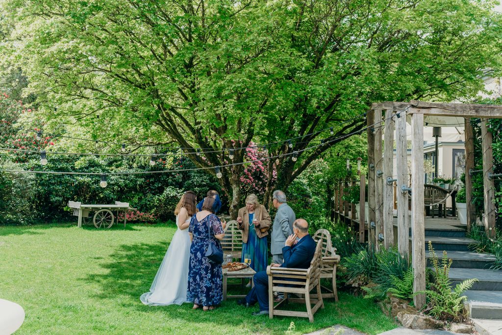 wedding guests under a tree with oak garden furniture
