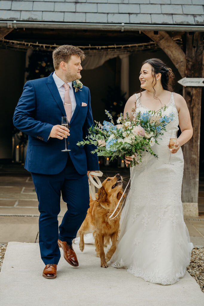 newly wed couple walking down aisle with golden retriever dog gazing up at bride