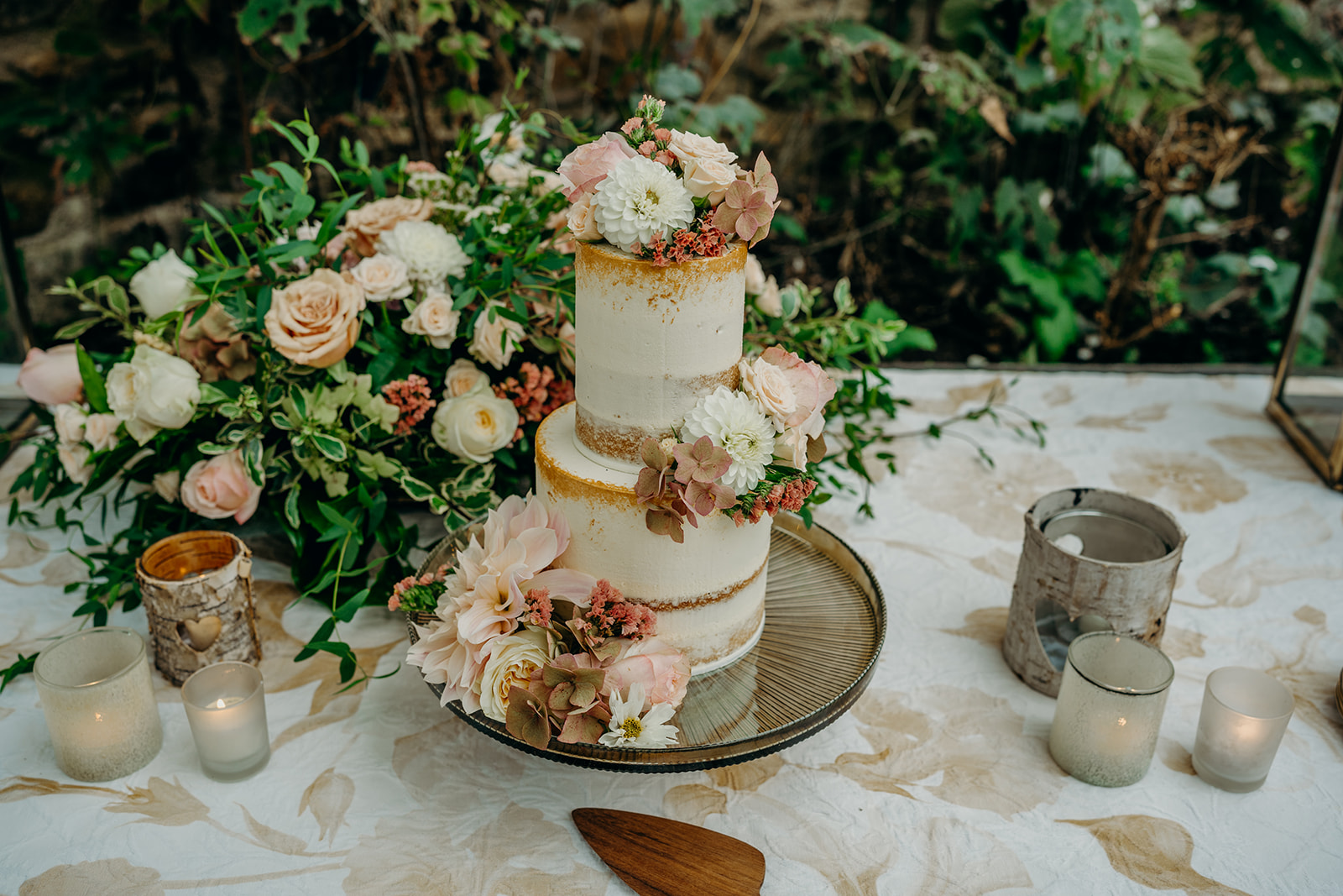 elopement cakes of 2023 on a linen dressed table with peach and nude fresh flowers and tea lights