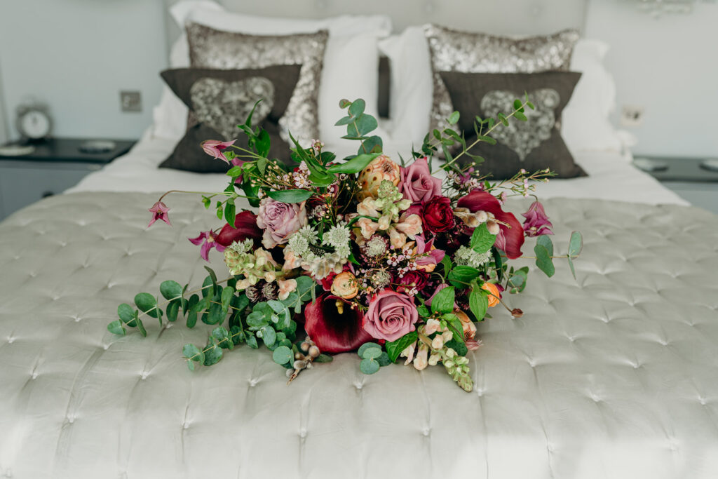 luxurious bridal bouquet in purple and pink colours on a silver grey silk bedspread