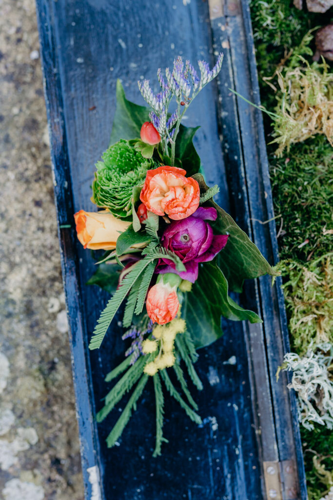 green and purple wedding corsage on a dark blue painted wooden board 
