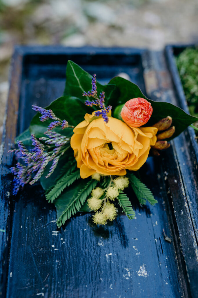 yellow rose wedding corsage on a dark blue painted wooden plank