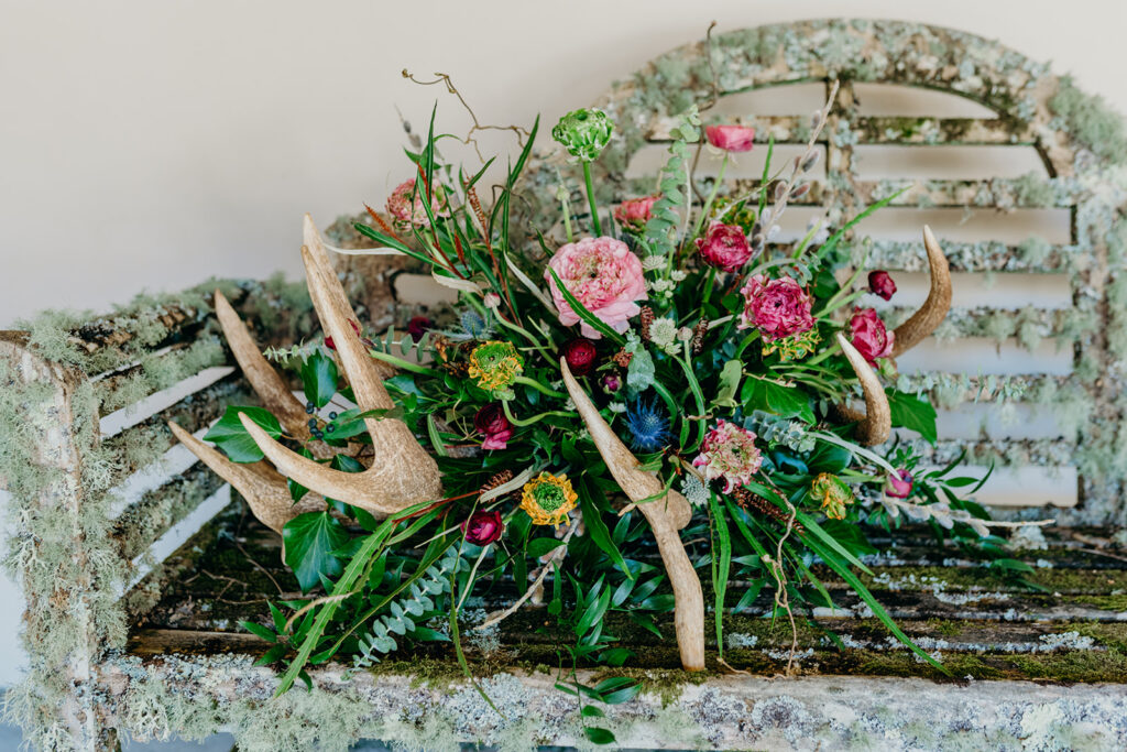 close up of antler wedding flowers on lichen covered Lutyens bench