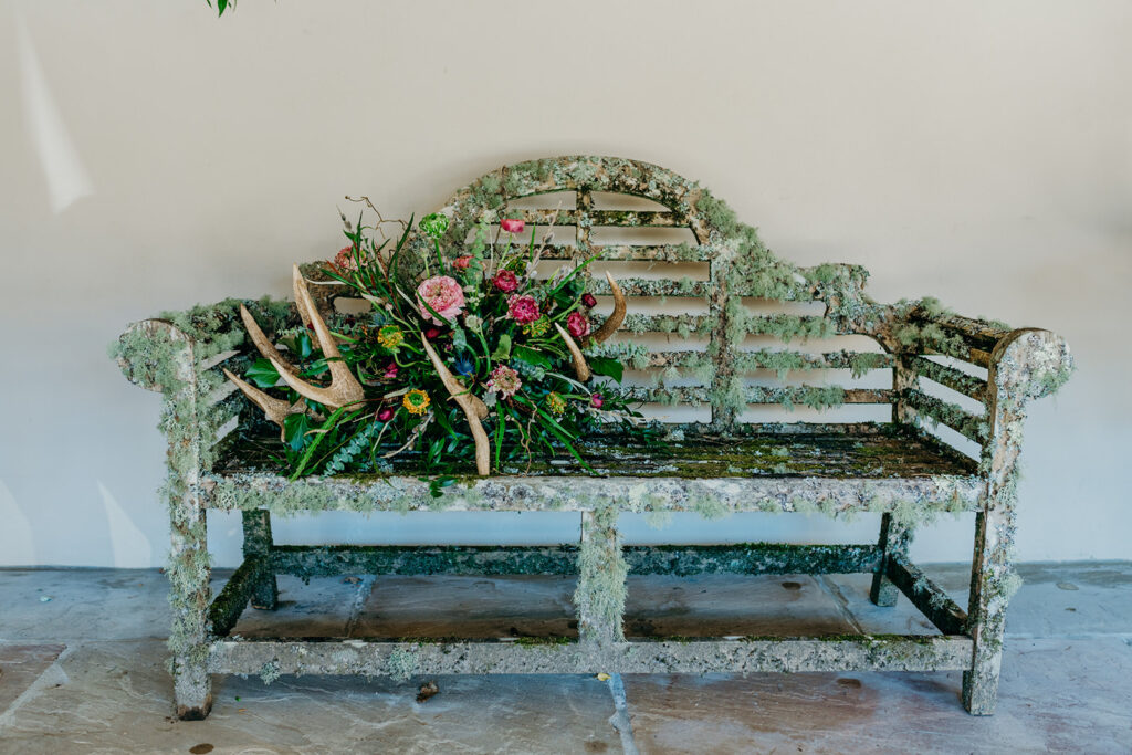 lichen covered Lutyens bench with wedding flower arrangement in antlers 