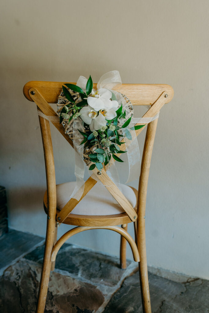 back view of bentwood chair with ivory cushion white orchid arrangement tied with white organza ribbon 