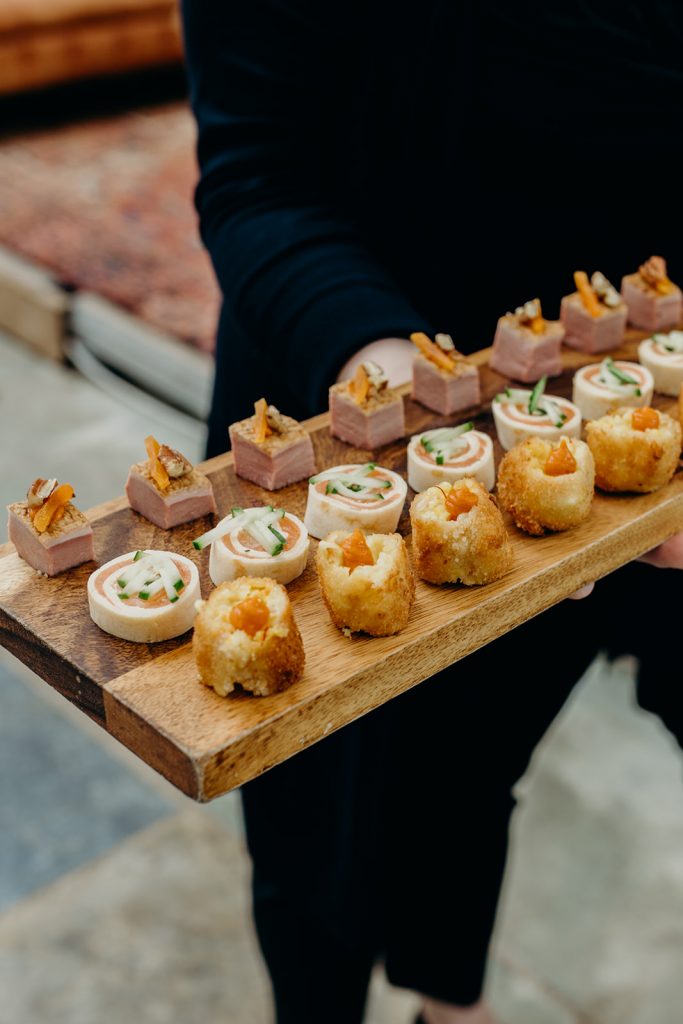 wooden board of canapes being held by server dressed in black