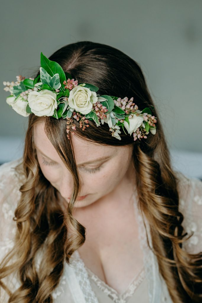 close up of bride wearing a half head flower crown of whie roses and foliage with long brown hair