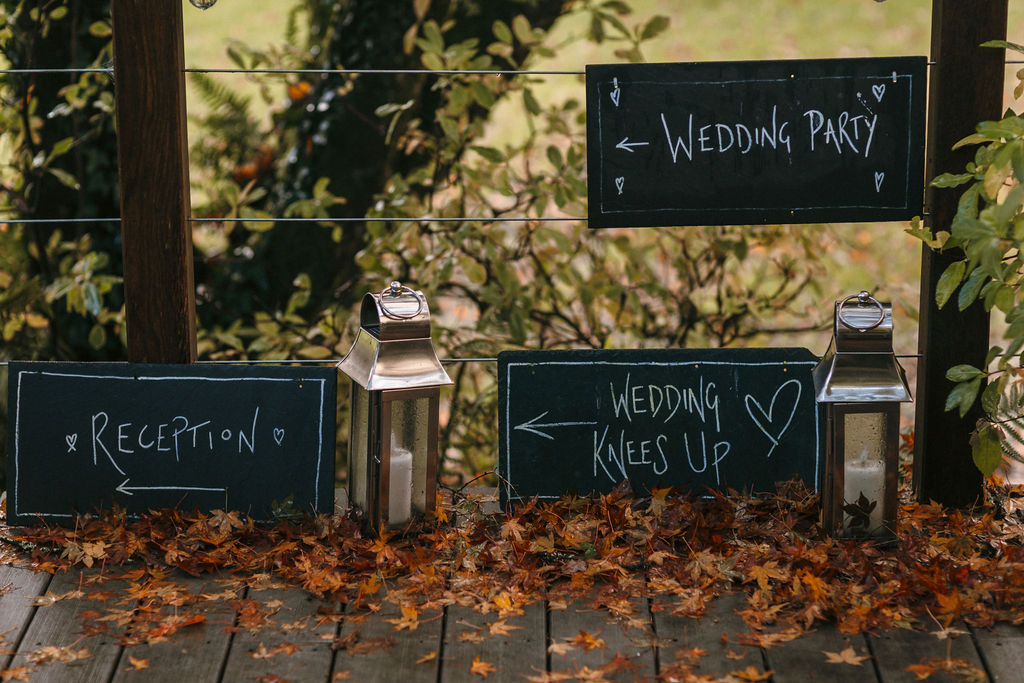 slate hand written wedding signs on fallen autumn leaves with steel lanterns 