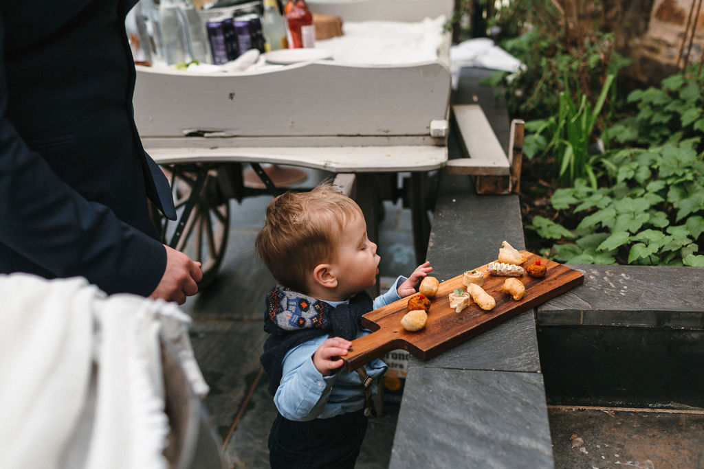 toddler boy looking at canapes on wooden board resting on slate