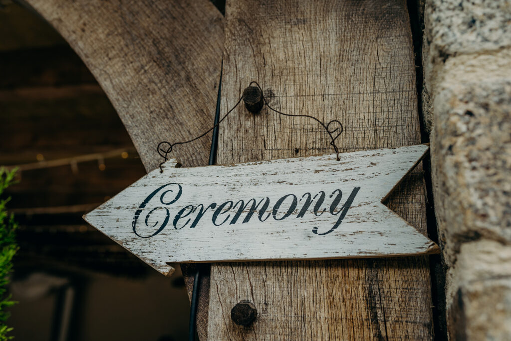 close up of oak beam with rustic ceremony sign hung on a wire