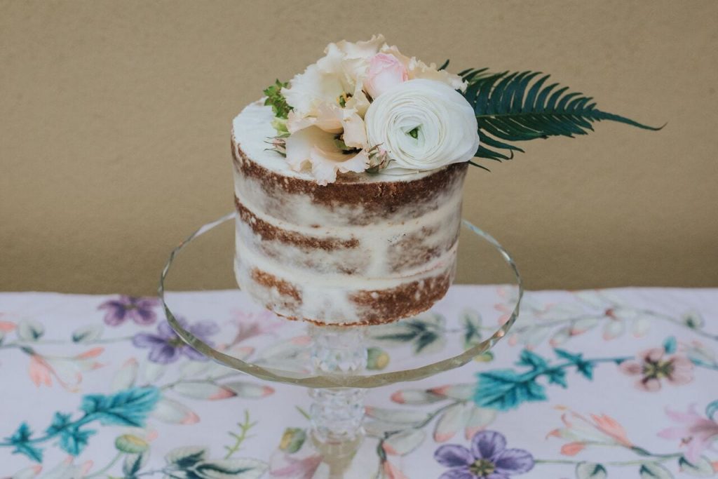 Miniature elopement naked wedding cake with white and peach flowers