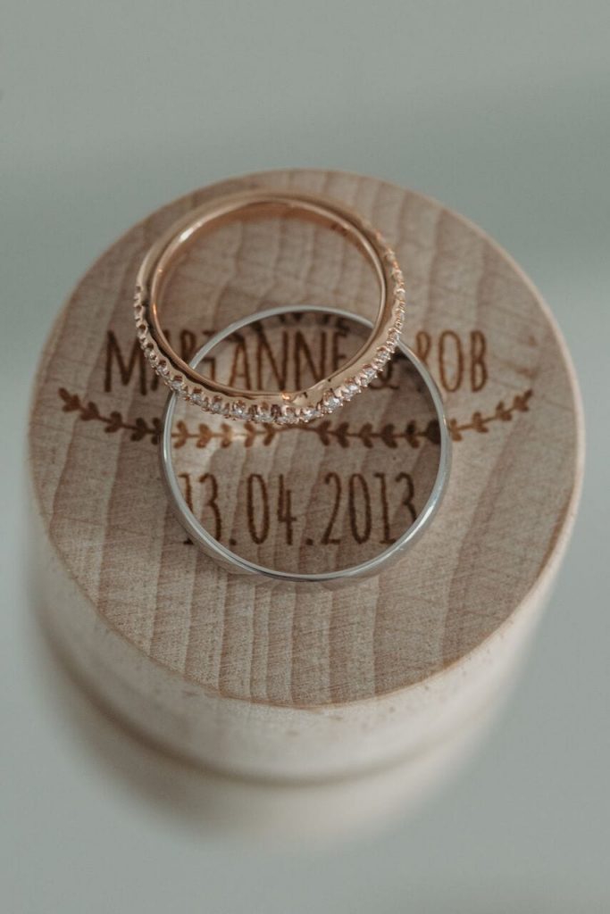 wedding rings on an engraved wooden box with couples names and wedding dates