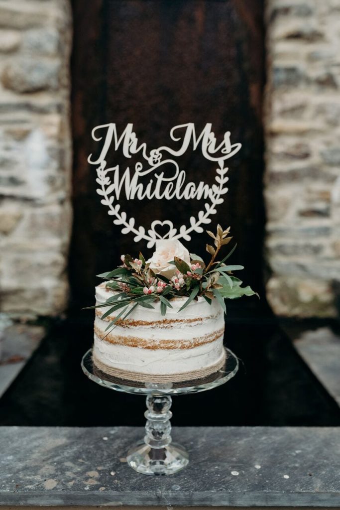 miniature elopement naked wedding cake withe greenery and a peach rose plus mr & mrs decor on top