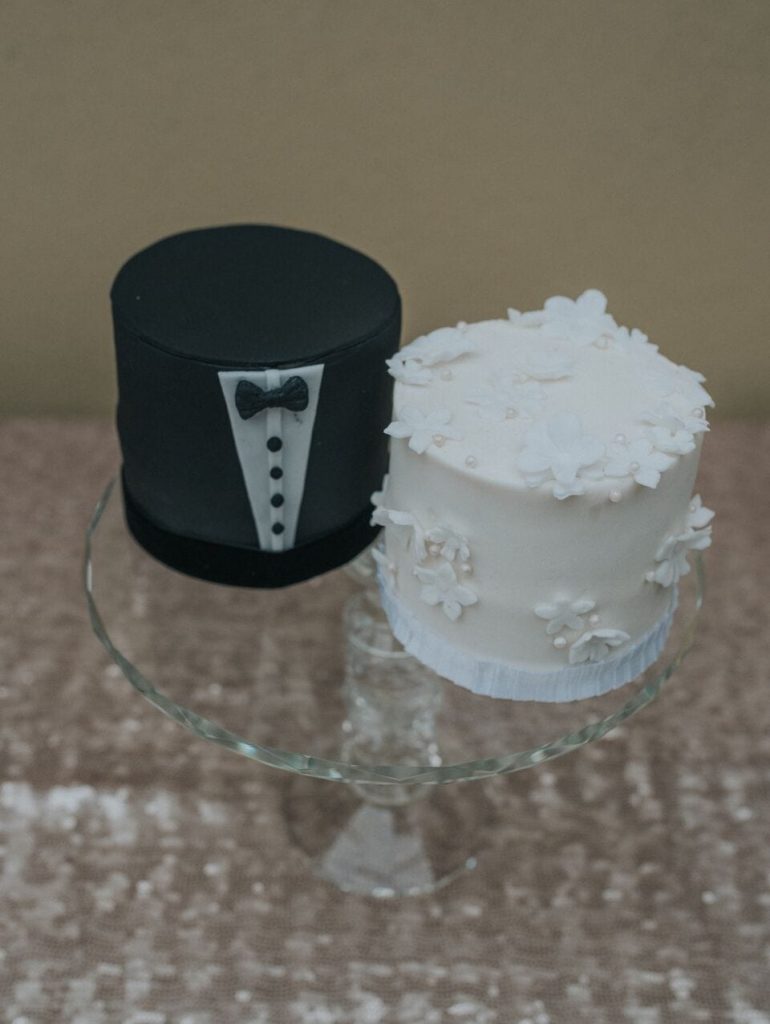 two very miniature elopement wedding cakes, one for the bride and one for the groom. The groom's cake is decorated with icing to look like a suit and the bride's is ivory icing with ivory flowers.