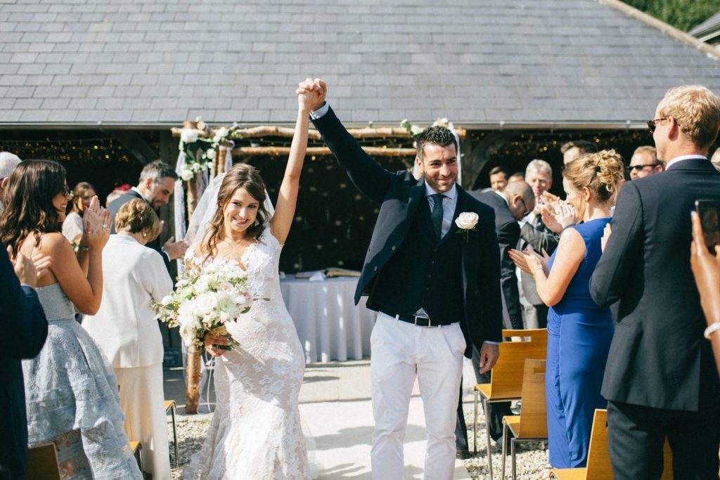 bride and groom outdoors celebrating hands in the air