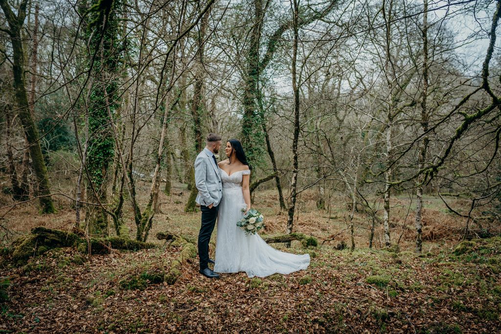 portrait of wedding couple looking at each other in bare tree woodland