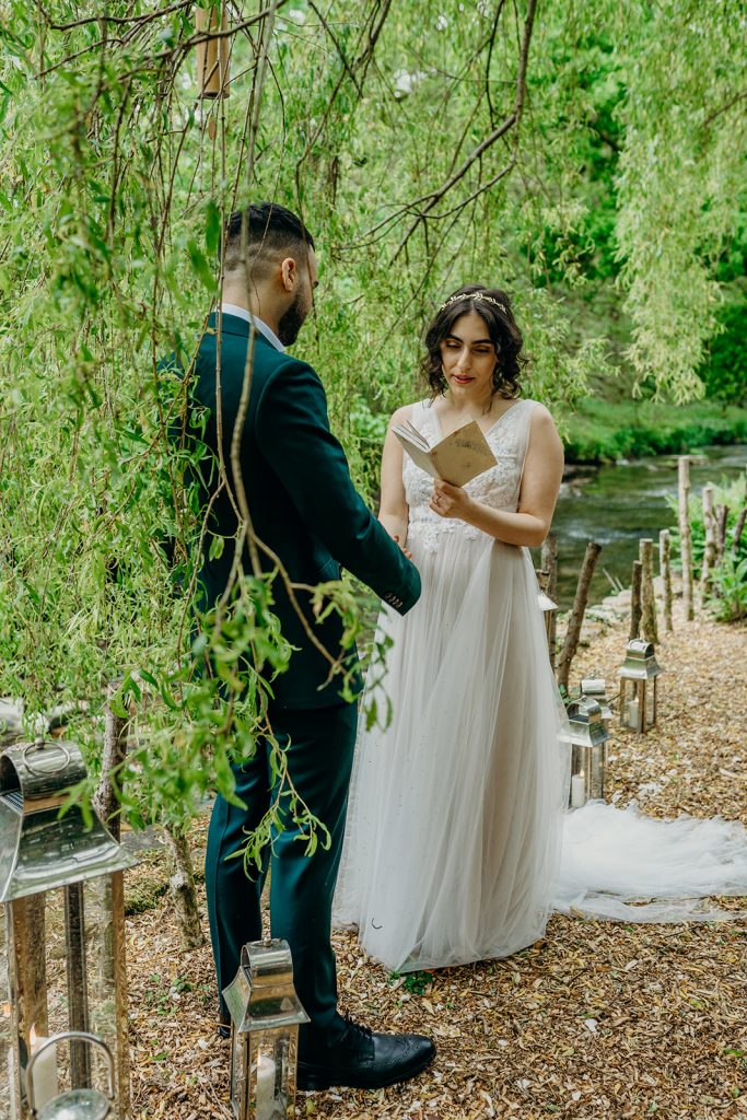 bride and groom in outdoor wedding ceremony reading vows