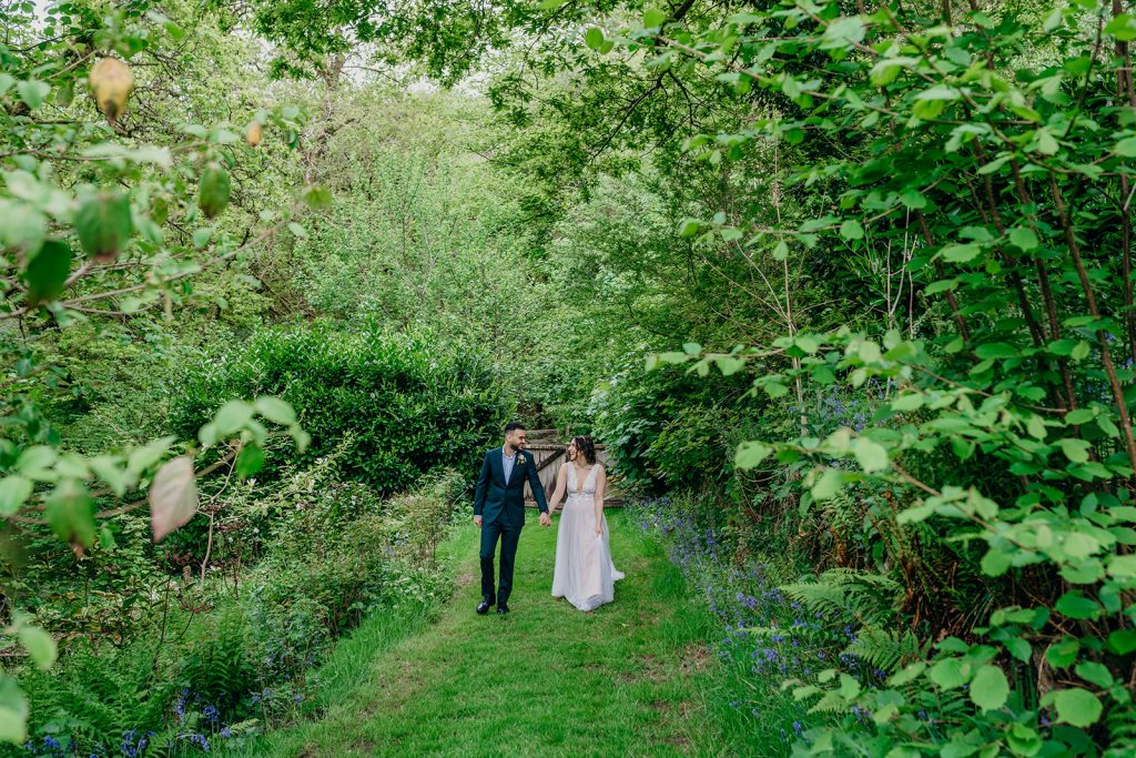 bride and groom walking on grass path surrounded by trees