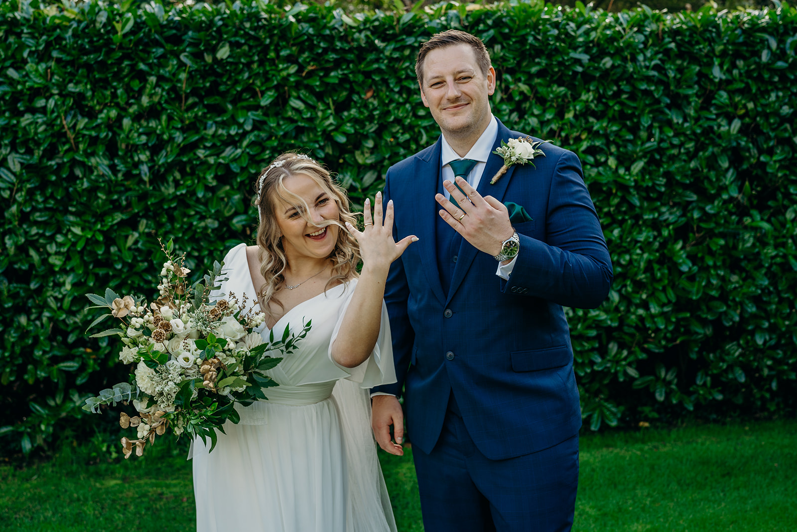 bride and groom holding up wedding ring fingers to show new wedding rings