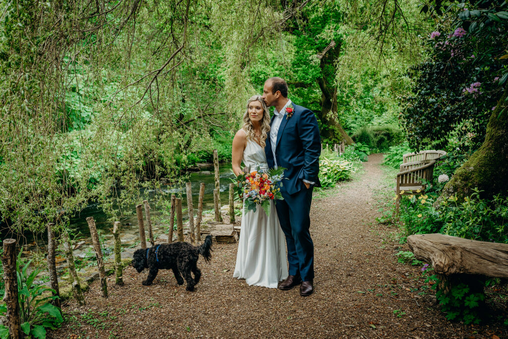 May 2023 elopement bouquet review bride and groom on riverside with dog bride holding bright bouquet 