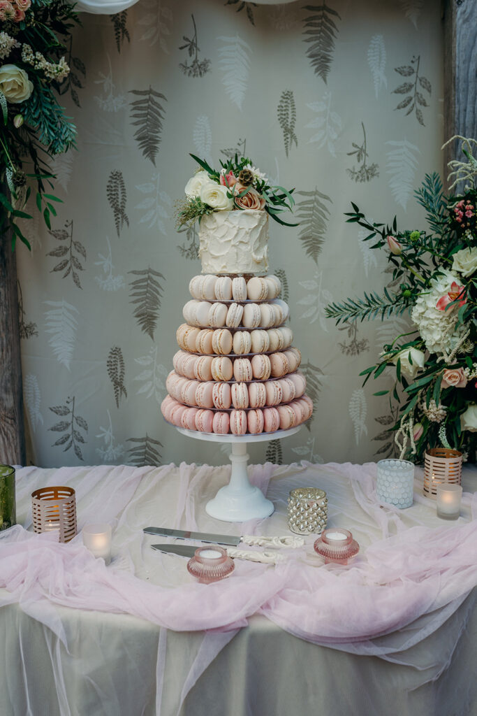 tiers of pink ombre macarons topped with rough butter cream mini cake dressed with fresh pink and white flowers