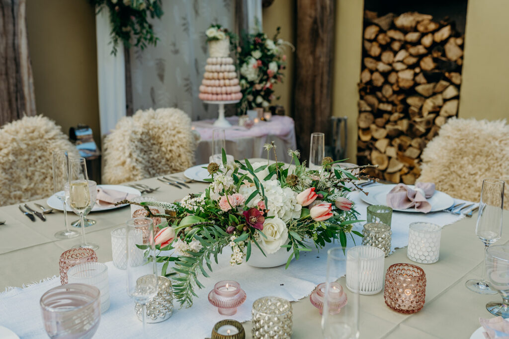 elopement wedding breakfast table set up with sheepskin rugs, green and pink, macaron tower wedding cake in background