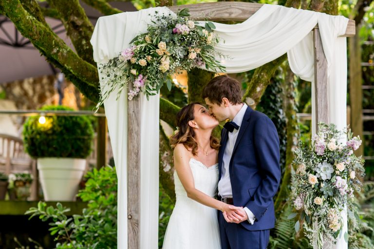 bride & groom kiss under floral arch