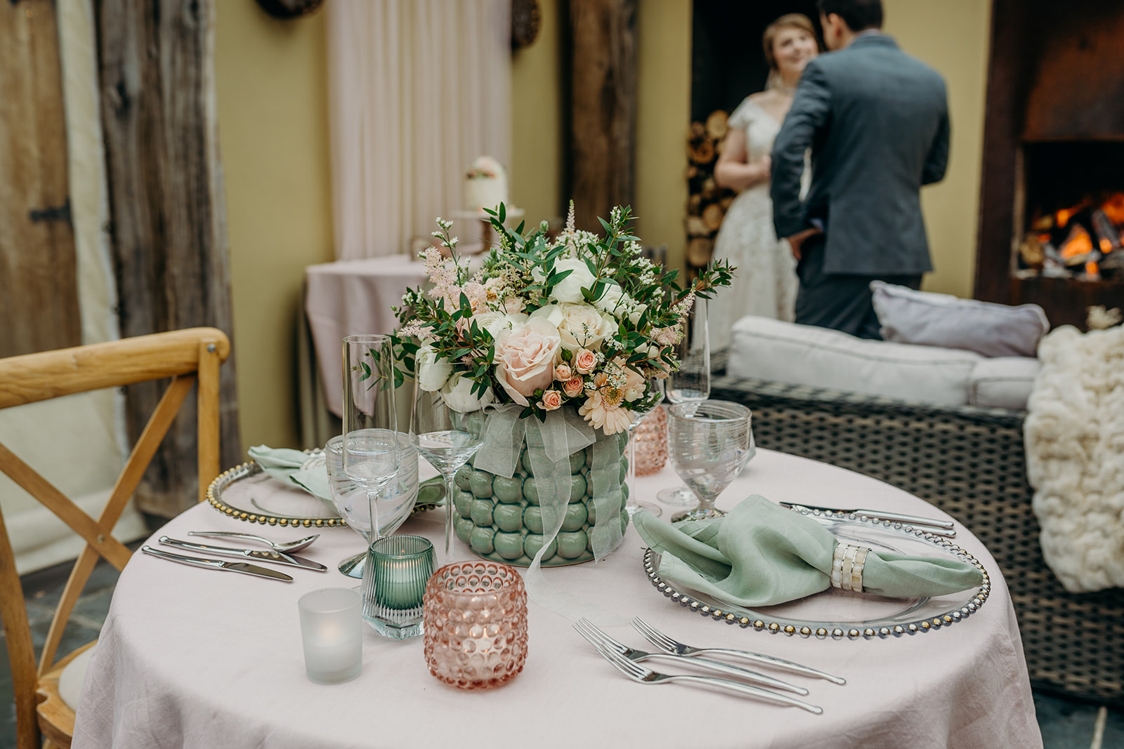 sweetheart wedding table dressed in pale pink and sage green with bride and groom in background